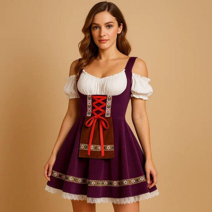 Model draagt een paarse dirndl met bruin schortje, rode strikveters, bloemenband langs de zoom en een kanten onderrok. 2