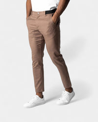 Model draagt de bruine slim fit broek met handen in de zakken en witte sneakers 5