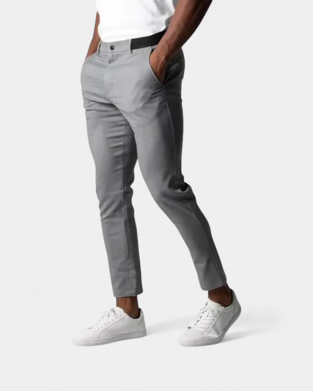 Model draagt de grijze slim fit broek met handen in de zakken en witte sneakers 1