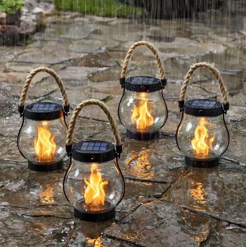 Vier brandende lantaarns met zonnepaneel op het deksel staan op natte stenen tegels in de regen 3