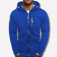 Koningsblauwe hoodie met capuchon en limoengroene ritstrekkers op een effen lichte achtergrond, gedragen door een man met handen in de zakken. 2