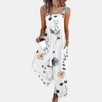 Model draagt de witte tuinbroek met fijne blauwe en oranje bloemenprint, vooraanzicht met koffiebeker 4