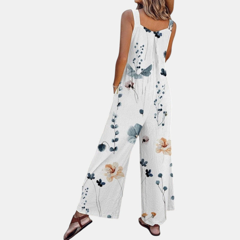 Achterzijde van de witte tuinbroek met bloemenprint, schuin gezien, met wijde pijpen en sandalen 5