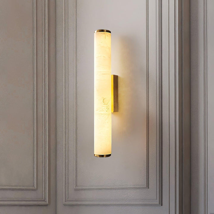 Verlichte marmeren wandlamp met koperkleurige afwerking tegen een wand met sierlijsten, met zichtbare adering in het gesteente. 18