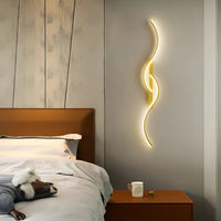 Gouden golvende wandlamp naast het hoofdeinde van een bed boven een nachtkastje in de slaapkamer 2