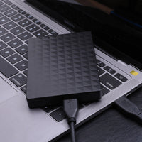 Zwarte harde schijf met USB 3.0-kabel liggend op het toetsenbord van een laptop 2