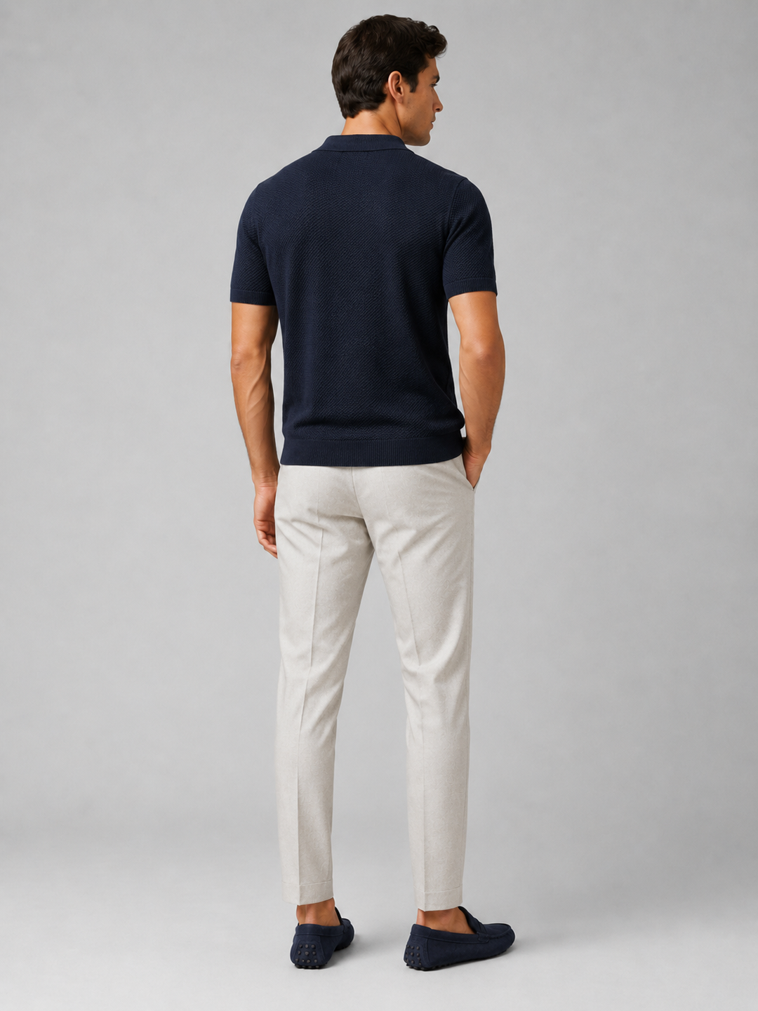 Achterzijde van het marineblauwe poloshirt met lichtgrijze pantalon en blauwe loafers 38