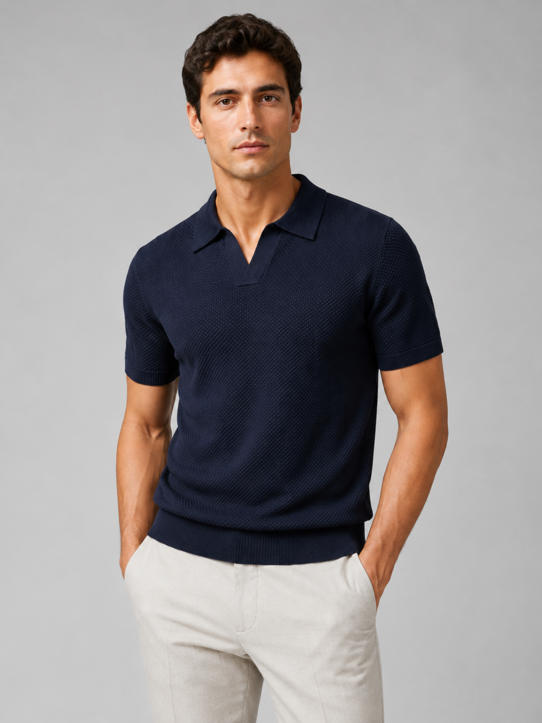 Man in marineblauw gebreid poloshirt met V-hals, handen in zakken van lichte broek 35