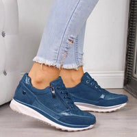 Blauwe sneakers met rits aan de zijkant en fijn gestippeld bovenwerk, gedragen met een lichtblauwe gescheurde spijkerbroek. 5