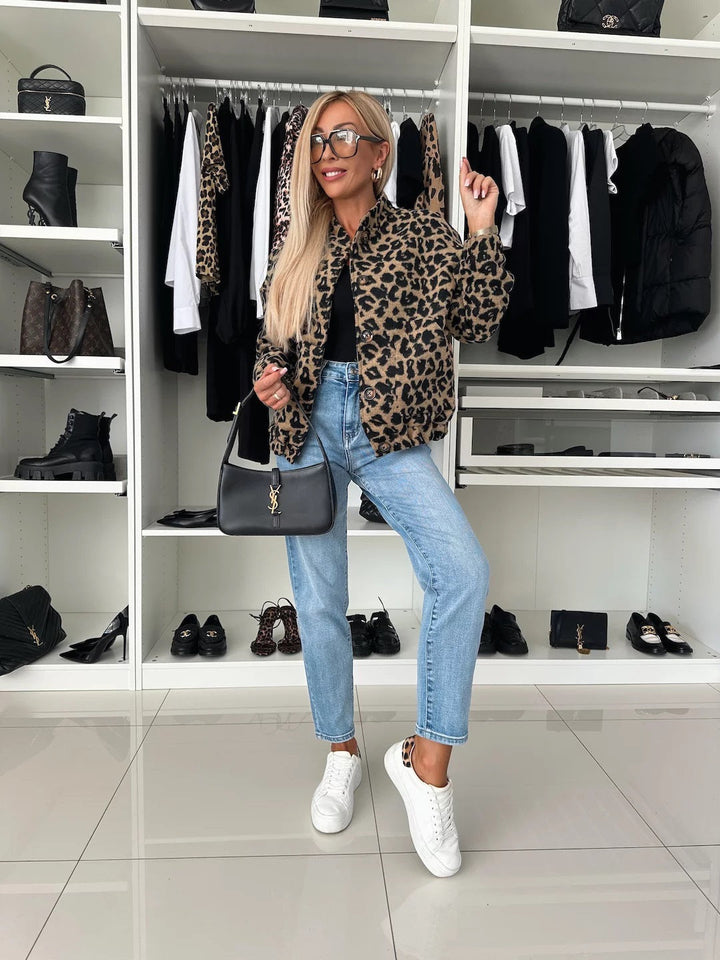 Model in volledige outfit: jasje met luipaardprint, zwarte top, lichtblauwe jeans, witte sneakers en een zwarte handtas in een inloopkast. 5
