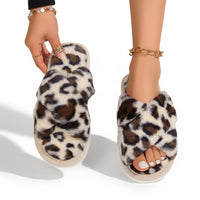 Pluche slippers met luipaardprint in crème en bruin; het model houdt één slipper omhoog en draagt de andere. 4