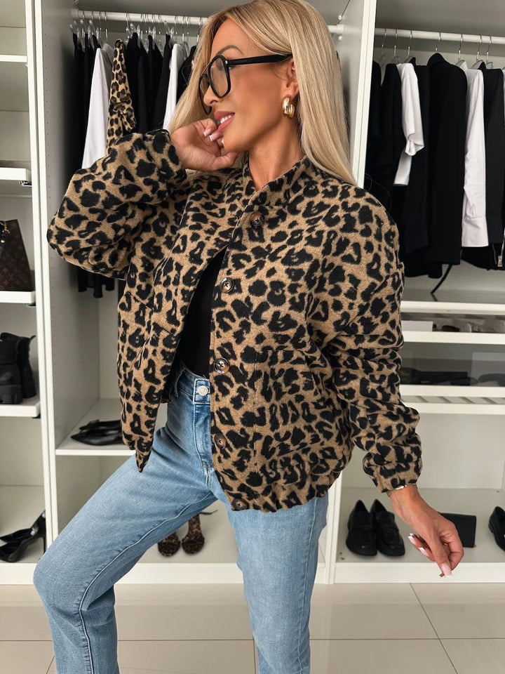 Model in dichtgeknoopt jasje met luipaardprint, schuin van opzij gefotografeerd, gedragen met een zwarte top en lichtblauwe jeans. 1