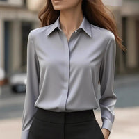 Model draagt de grijze blouse met puntkraag, verdekte sluiting en lange mouwen, gecombineerd met zwarte broek 2