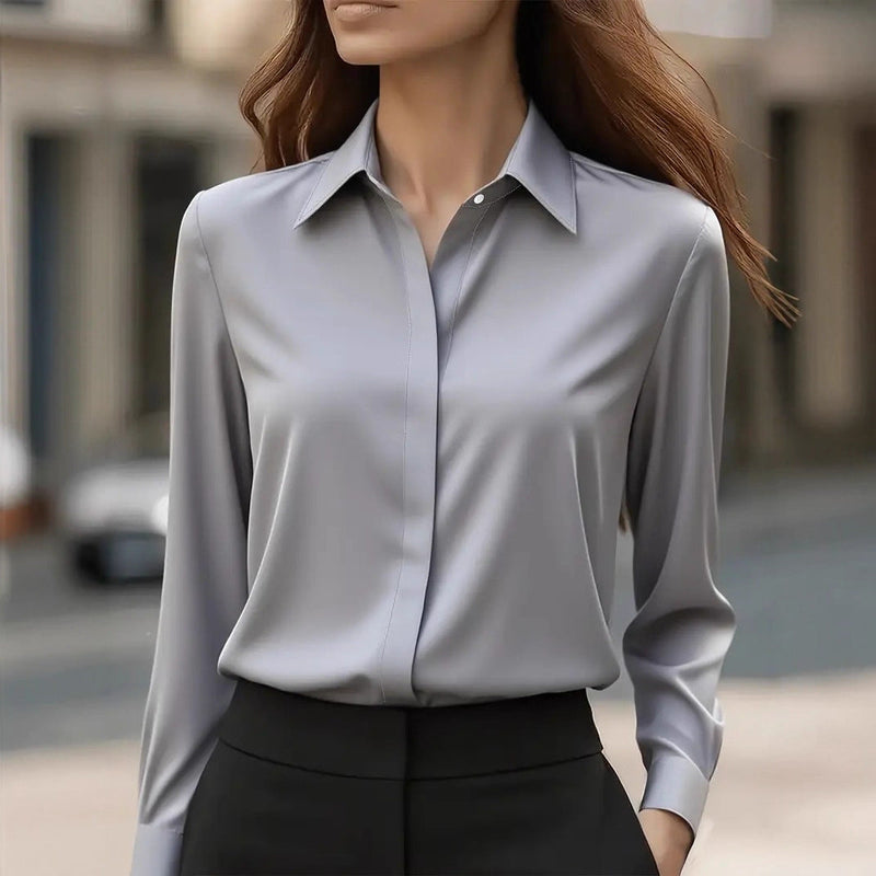 Model draagt de grijze blouse met puntkraag, verdekte sluiting en lange mouwen, gecombineerd met zwarte broek 2