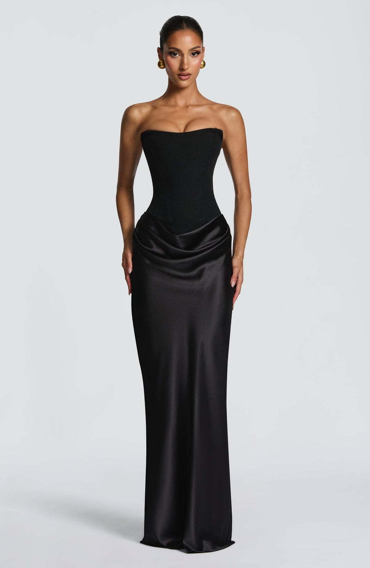 Zwarte strapless korsetjurk van satijn, voorkant, gedragen door een model met strakke knot en gouden oorbellen 21