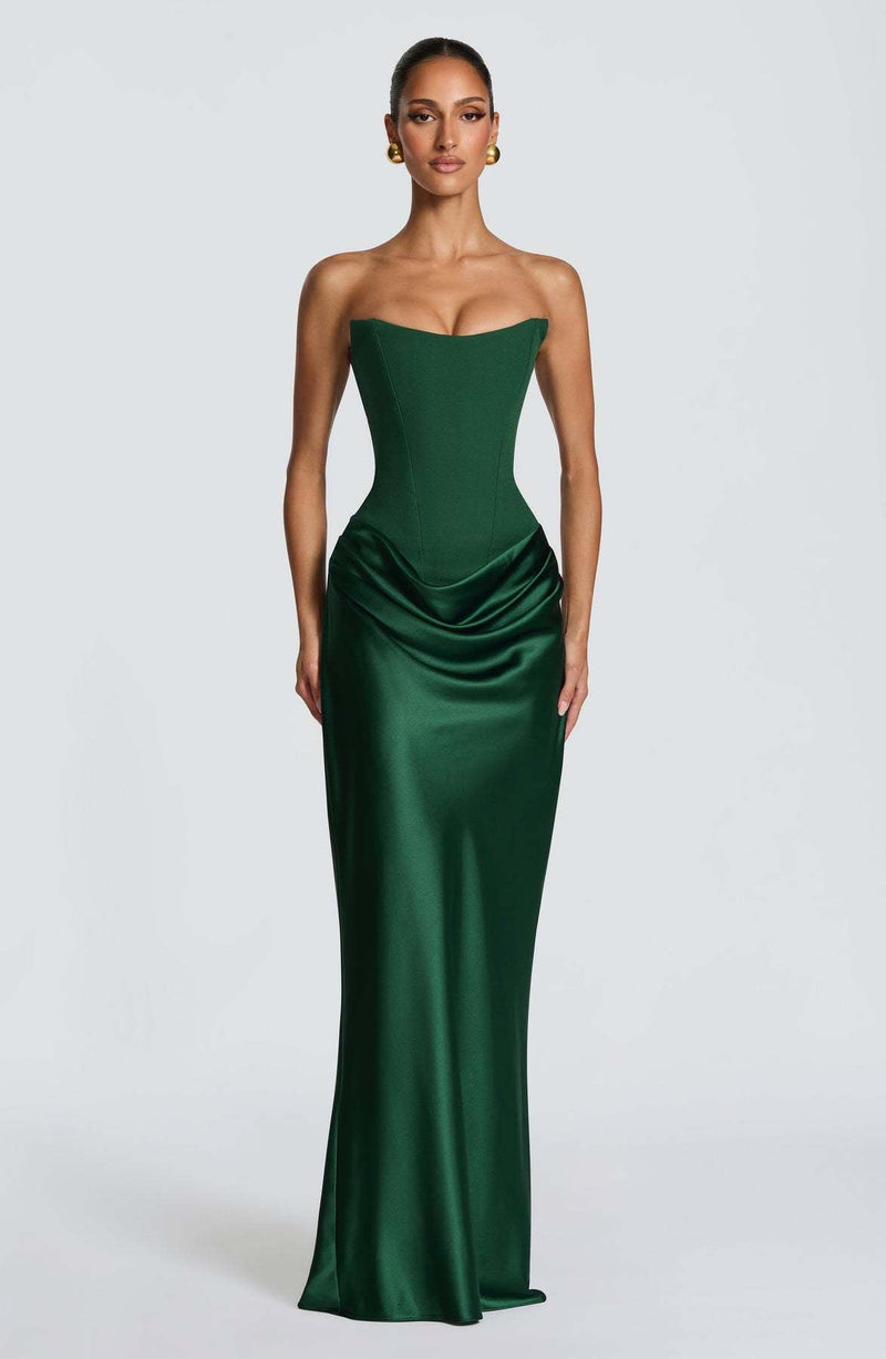 Model in smaragdgroene strapless korsetjurk met satijnen rok, frontaal tegen lichtgrijze achtergrond 1