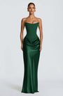 Model in smaragdgroene strapless korsetjurk met satijnen rok, frontaal tegen lichtgrijze achtergrond 1