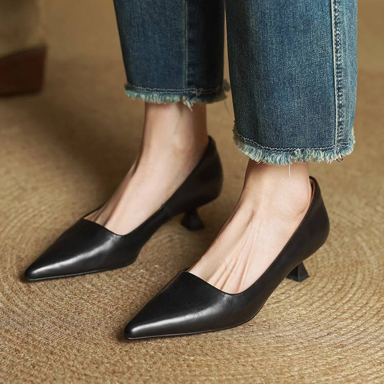 Zwarte pumps gedragen met jeans met rafelrand, beide schoenen staand op een gevlochten ondergrond 13