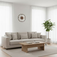 Wandklok boven een beige bank met salontafel en bladplant in een lichte woonkamer 3