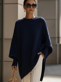 Model draagt de oversized trui in donkerblauw met witte broek, zonnebril en beige tas. 8