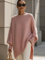Model draagt de oversized trui in roze met witte broek, zonnebril en beige tas. 11