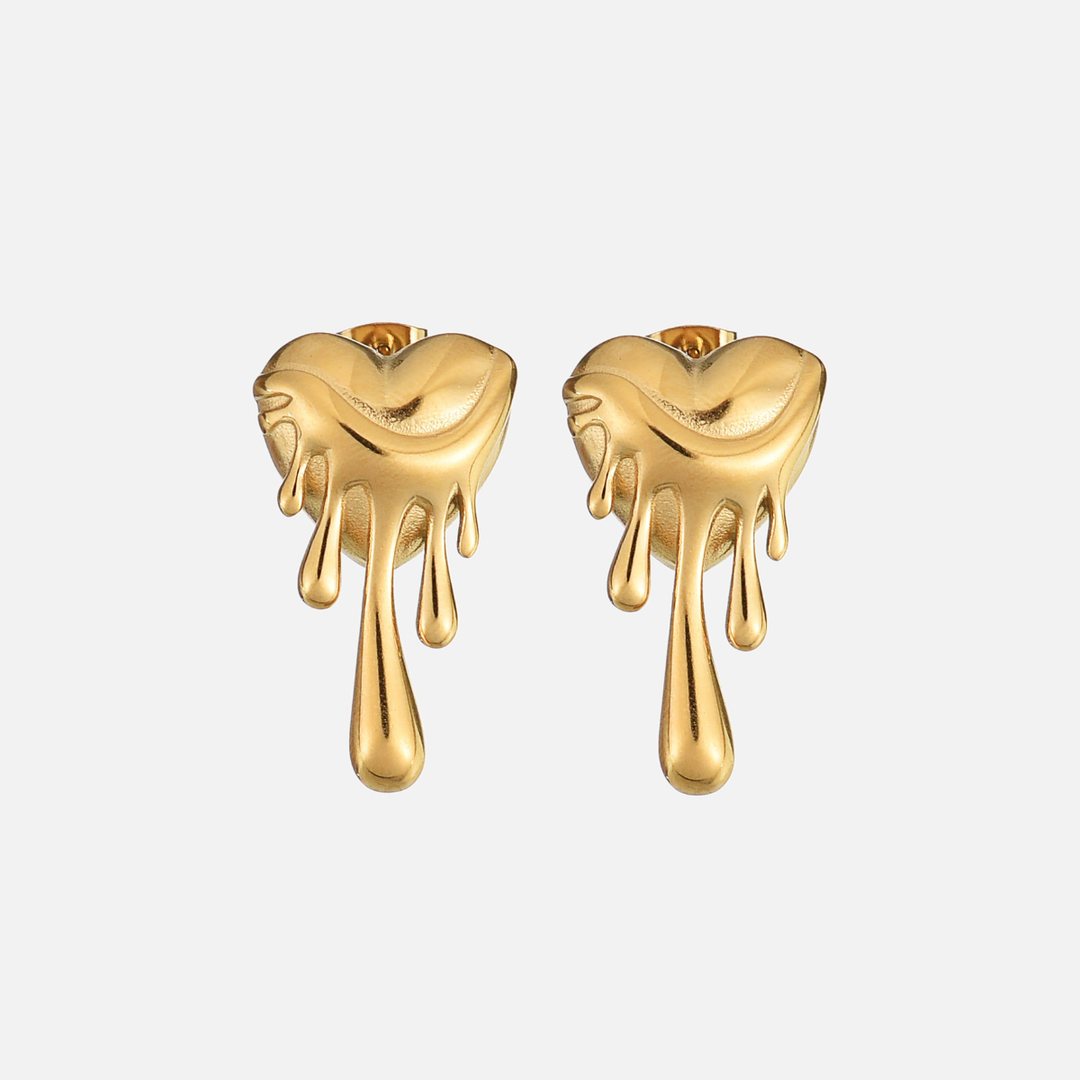 Voorkant van een paar gouden hartvormige oorstekers met druipende druppels, op een lichtgrijze achtergrond. 1