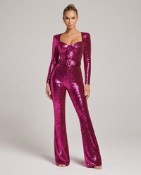 Model in fuchsia roze pailletten jumpsuit, voorkant, staand met armen langs het lichaam, hartvormige halslijn, riem en uitlopende pijpen. 1