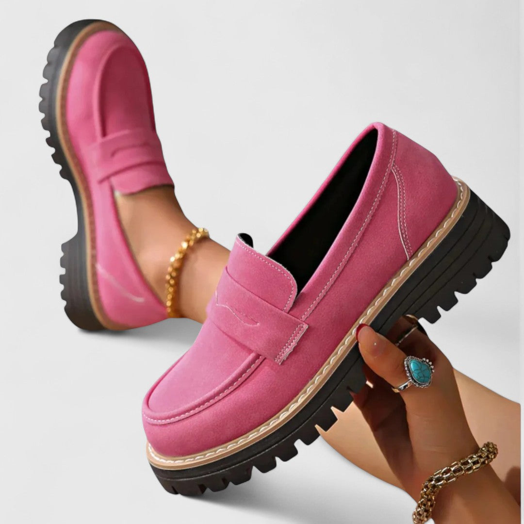 Roze loafers met stevige profielzool, de ene vastgehouden in de hand, de andere gedragen 3