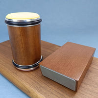 Houten cilinder met geel schuurschijfje bovenop, naast het hoekblok, op een houten plank voor een blauwe achtergrond. 5