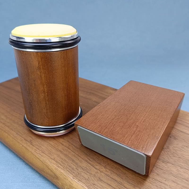 Houten cilinder met geel schuurschijfje bovenop, naast het hoekblok, op een houten plank voor een blauwe achtergrond. 5