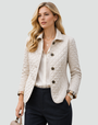 Crèmewitte gewatteerde jas met ruitstiksels en knoopsluiting, gedragen over een witte blouse met donkere pantalon en handtas. 2