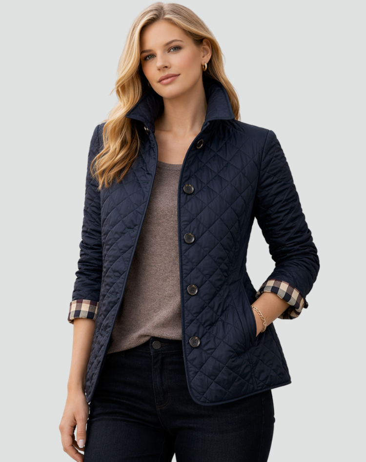Donkerblauwe gewatteerde jas met ruitstiksels en geruite mouwomslag, gedragen over een taupe top en donkere broek. 5