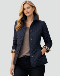 Donkerblauwe gewatteerde jas met ruitstiksels en geruite mouwomslag, gedragen over een taupe top en donkere broek. 5