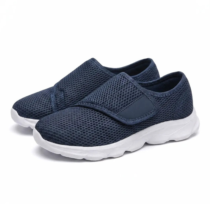 Schuin aanzicht van een paar donkerblauwe mesh schoenen met klittenbandsluiting en witte zool. 7