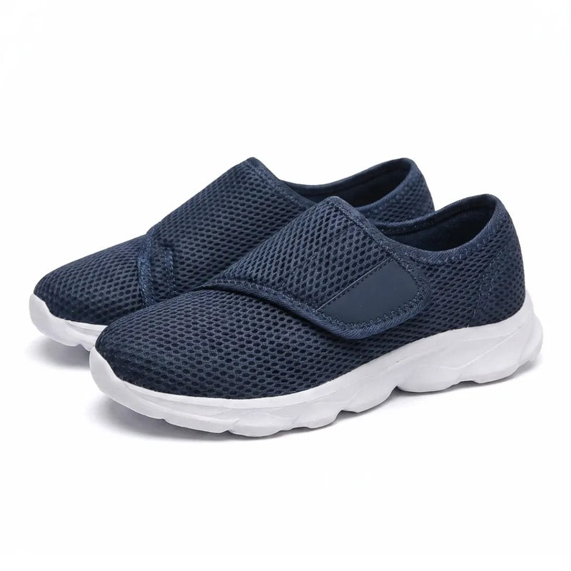 Schuin aanzicht van een paar donkerblauwe mesh schoenen met klittenbandsluiting en witte zool. 7