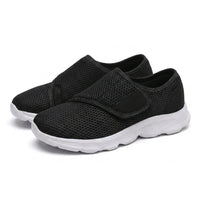 Paar zwarte mesh schoenen met witte zool en klittenbandsluiting, schuin van voren gefotografeerd. 25