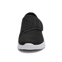 Zwarte mesh schoen van voren gezien, met de brede neus, het klittenbandriempje en de witte zool. 26
