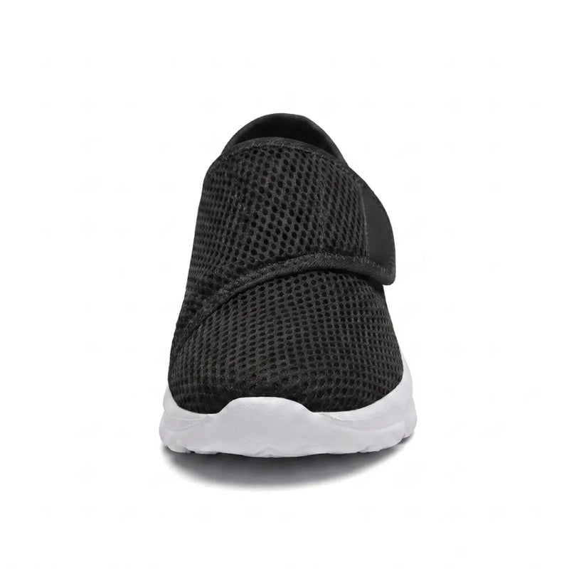 Zwarte mesh schoen van voren gezien, met de brede neus, het klittenbandriempje en de witte zool. 26