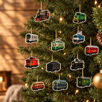 Twaalf hangertjes in de vorm van treinen en wagons, in verschillende kleuren, hangen aan gouden draadjes in een verlichte kerstboom. 1