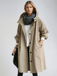 Model draagt de beige trenchcoat met opstaande kraag en knoopsluiting over een wit shirt, met donkere sjaal om de nek. 3