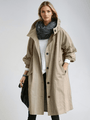 Model draagt de beige trenchcoat met opstaande kraag en knoopsluiting over een wit shirt, met donkere sjaal om de nek. 3