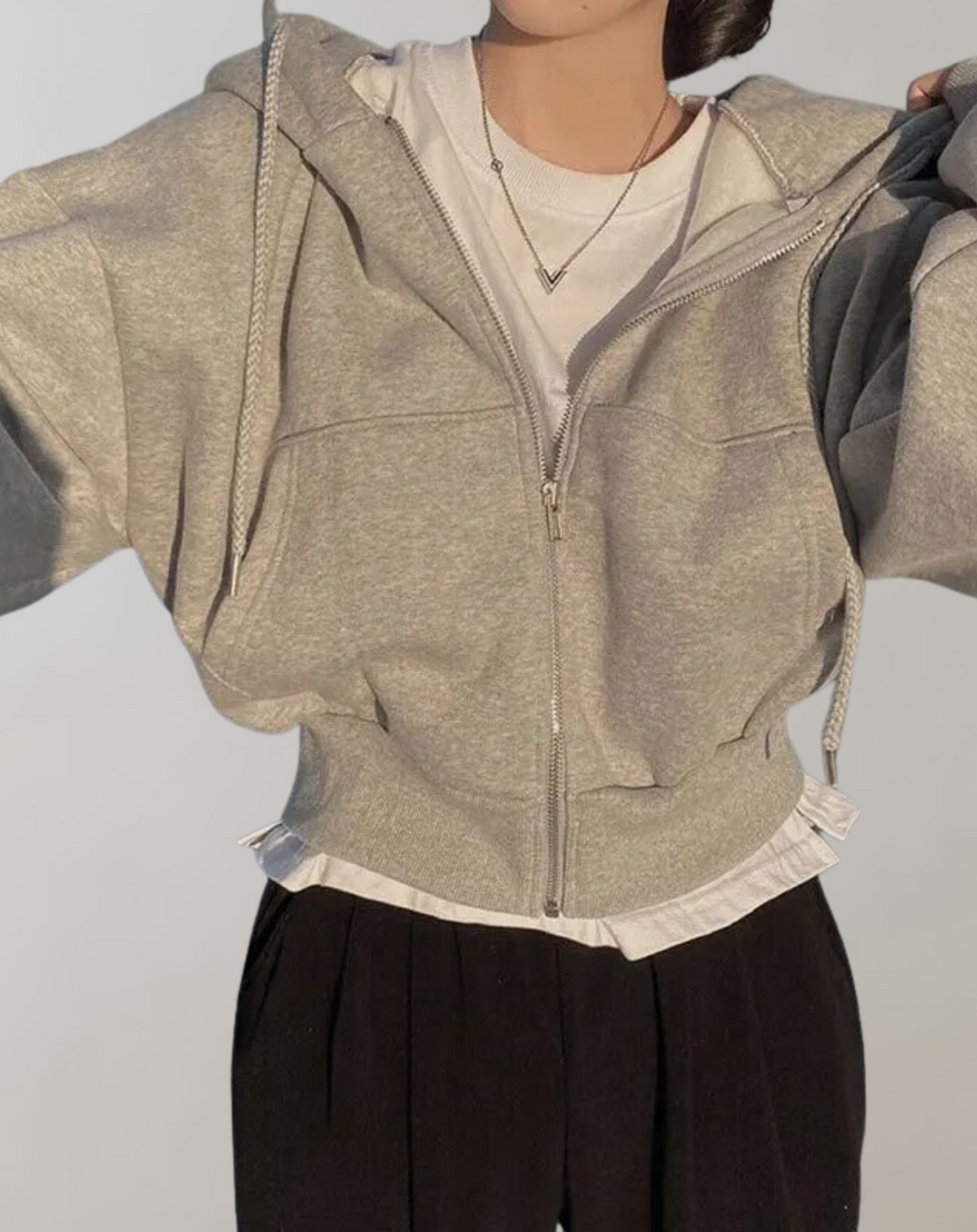 Gemêleerd grijze hoodie met geopende rits over een wit shirt, gecombineerd met een zwarte broek, met geribde manchetten en onderrand. 5