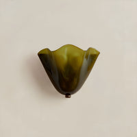 Olijfgroene glazen wandlamp met golvende rand en klein metalen knopje onderaan, uitgeschakeld tegen een effen lichte muur. 6