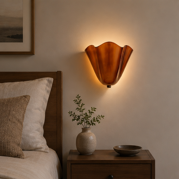 Verlichte bruine wandlamp met golvende rand boven een houten nachtkastje naast een bed met kussens en een ingelijste kunstwerk. 9