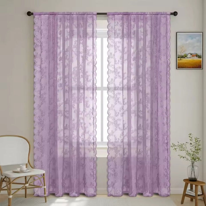 Twee lila doorzichtige kantgordijnen met bloemenpatroon en golvende zijkant aan een donkere roede voor een raam in een lichte kamer. 10