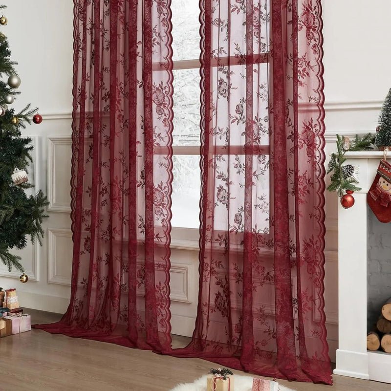 Twee donkerrode doorzichtige kantgordijnen met bloemenpatroon voor een raam, in een kamer met kerstboom en open haard. 2