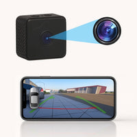 Zwarte kubusvormige camera met uitvergrote lens en een smartphone die het achteruitrijbeeld met groene en rode hulplijnen toont. 2