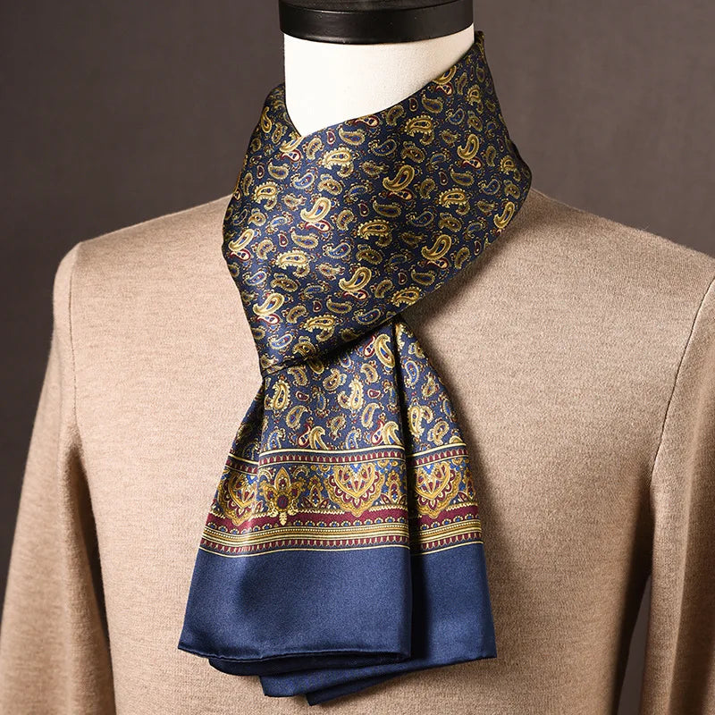 Marineblauwe zijden sjaal met gouden paisleymotieven en bordeauxrode sierrand, op een paspop met beige trui. 12