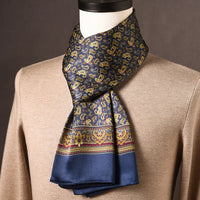 Marineblauwe zijden sjaal met gouden paisleymotieven en bordeauxrode sierrand, op een paspop met beige trui. 12