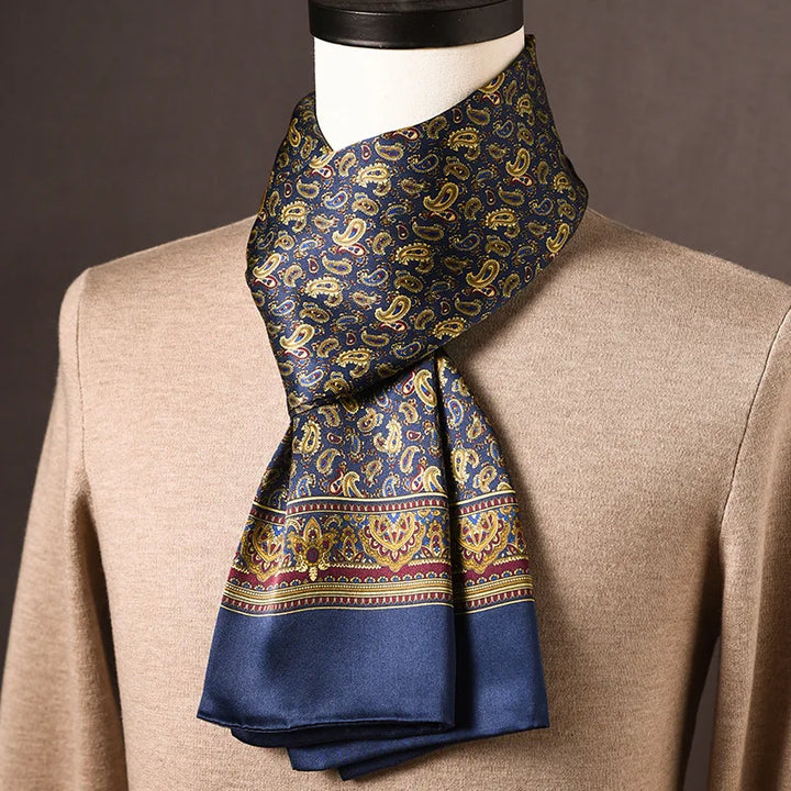 Marineblauwe zijden sjaal met gouden paisleymotieven en bordeauxrode sierrand, op een paspop met beige trui. 12